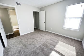 A bedroom with a carpeted floor and a large window